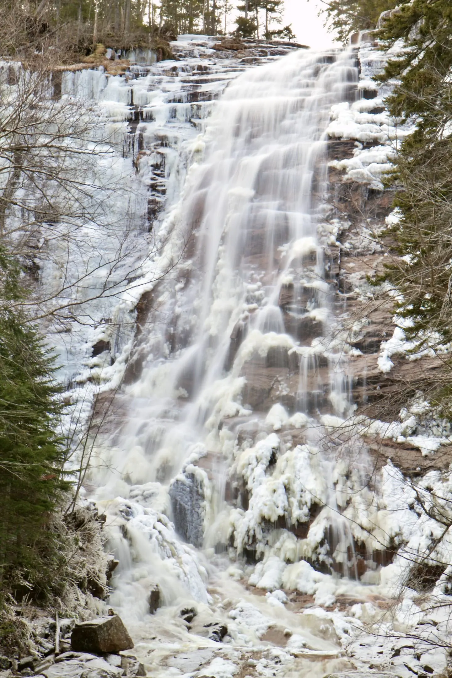 A waterfall with snow on the ground and trees