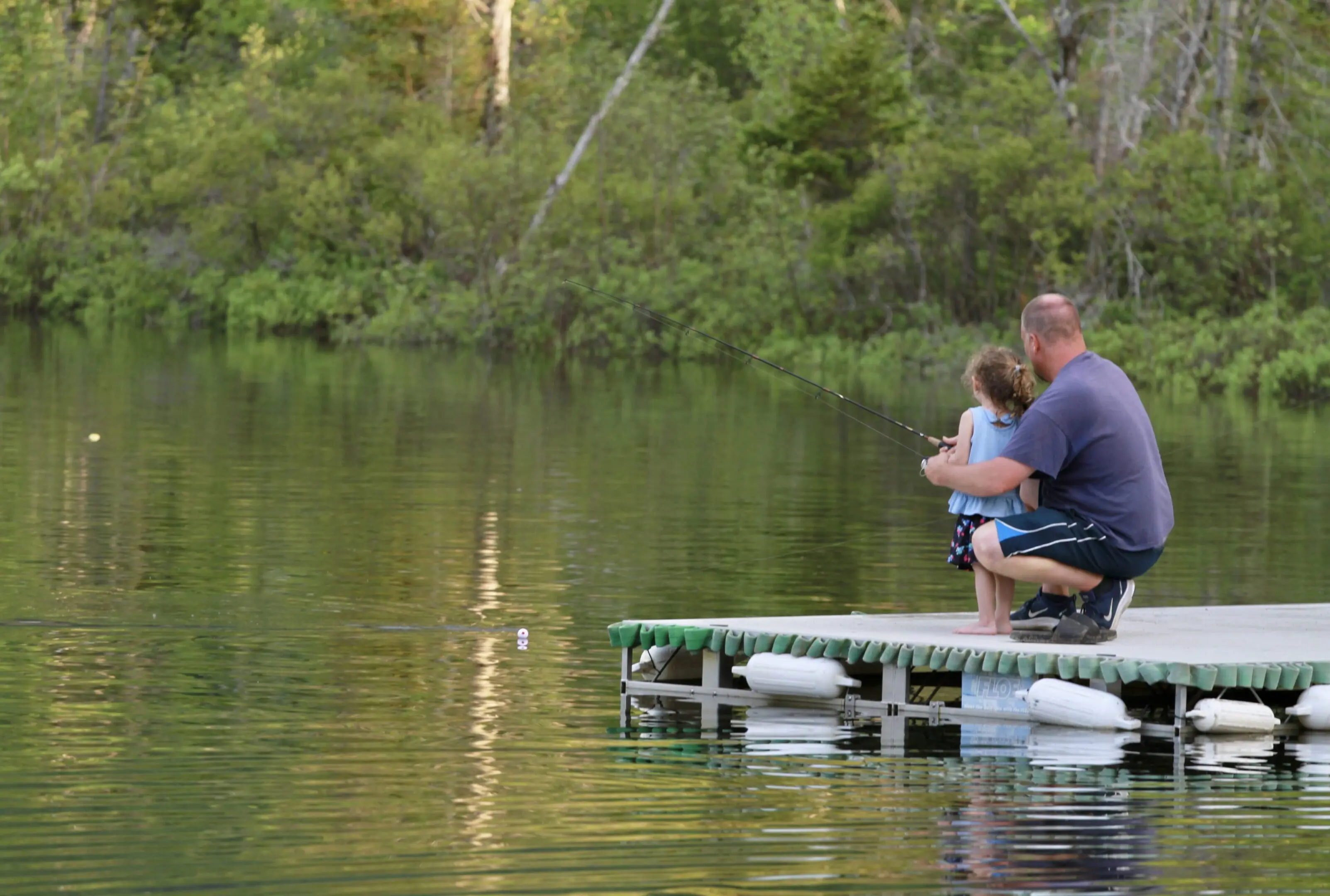 A man and child fishing on the dock.