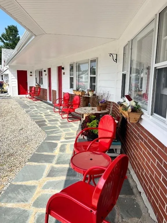 A red chair and some chairs on the side of a building.