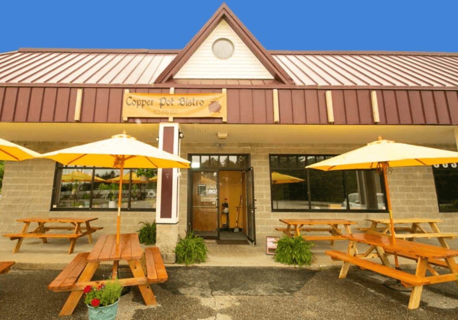 A restaurant with tables and umbrellas outside of it