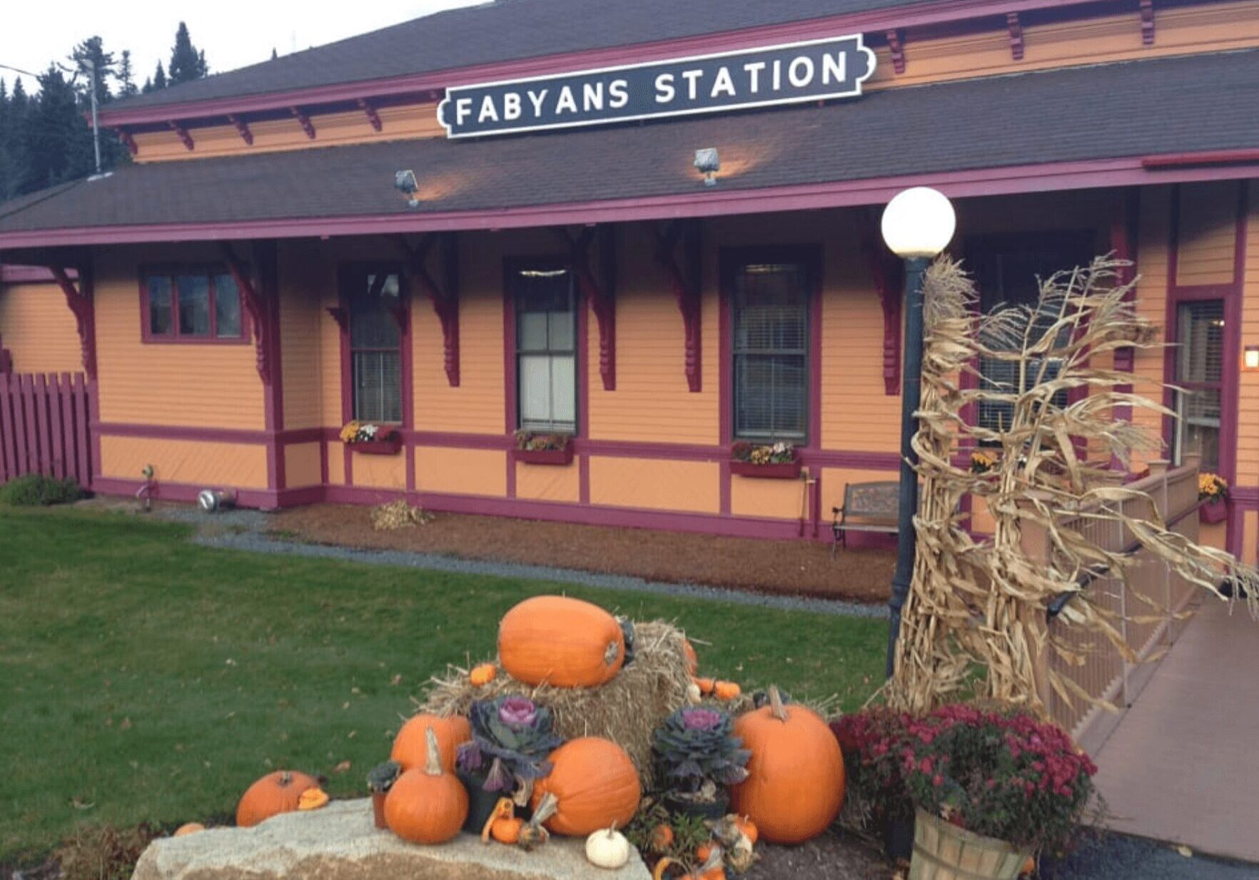 A bunch of pumpkins are in front of the train station.