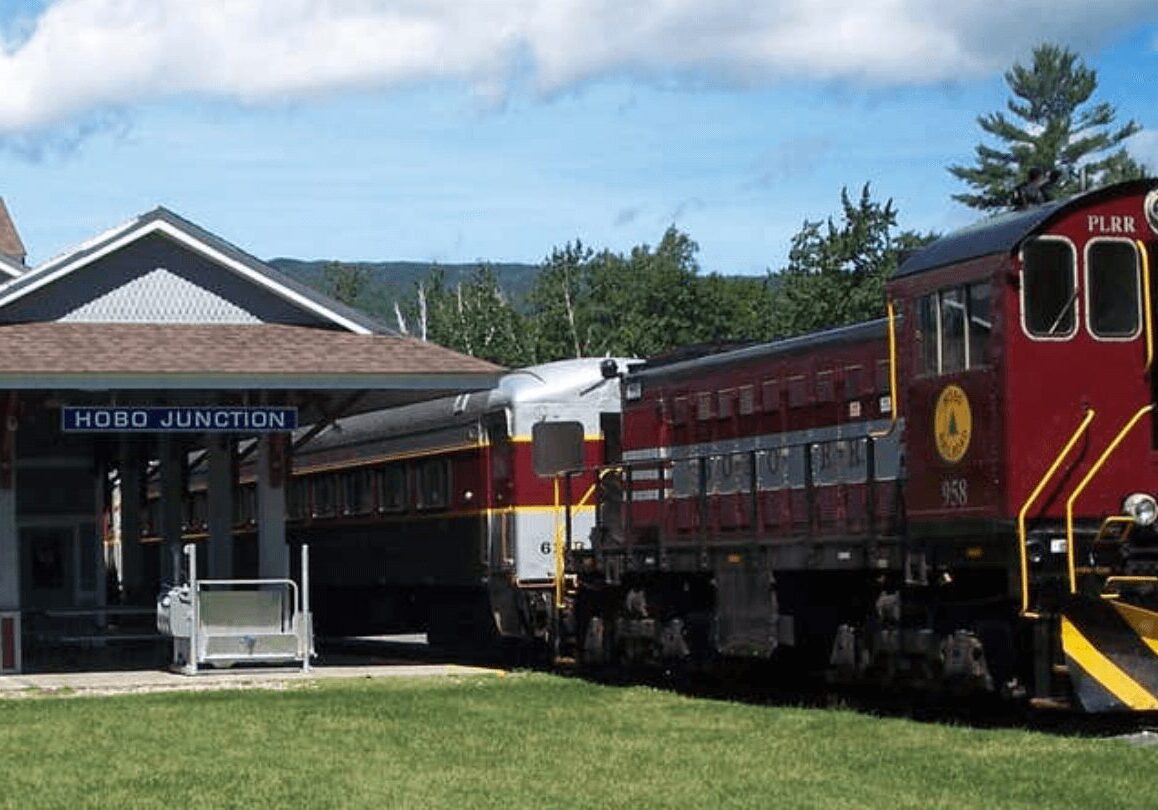 A train is parked at the station with people waiting.